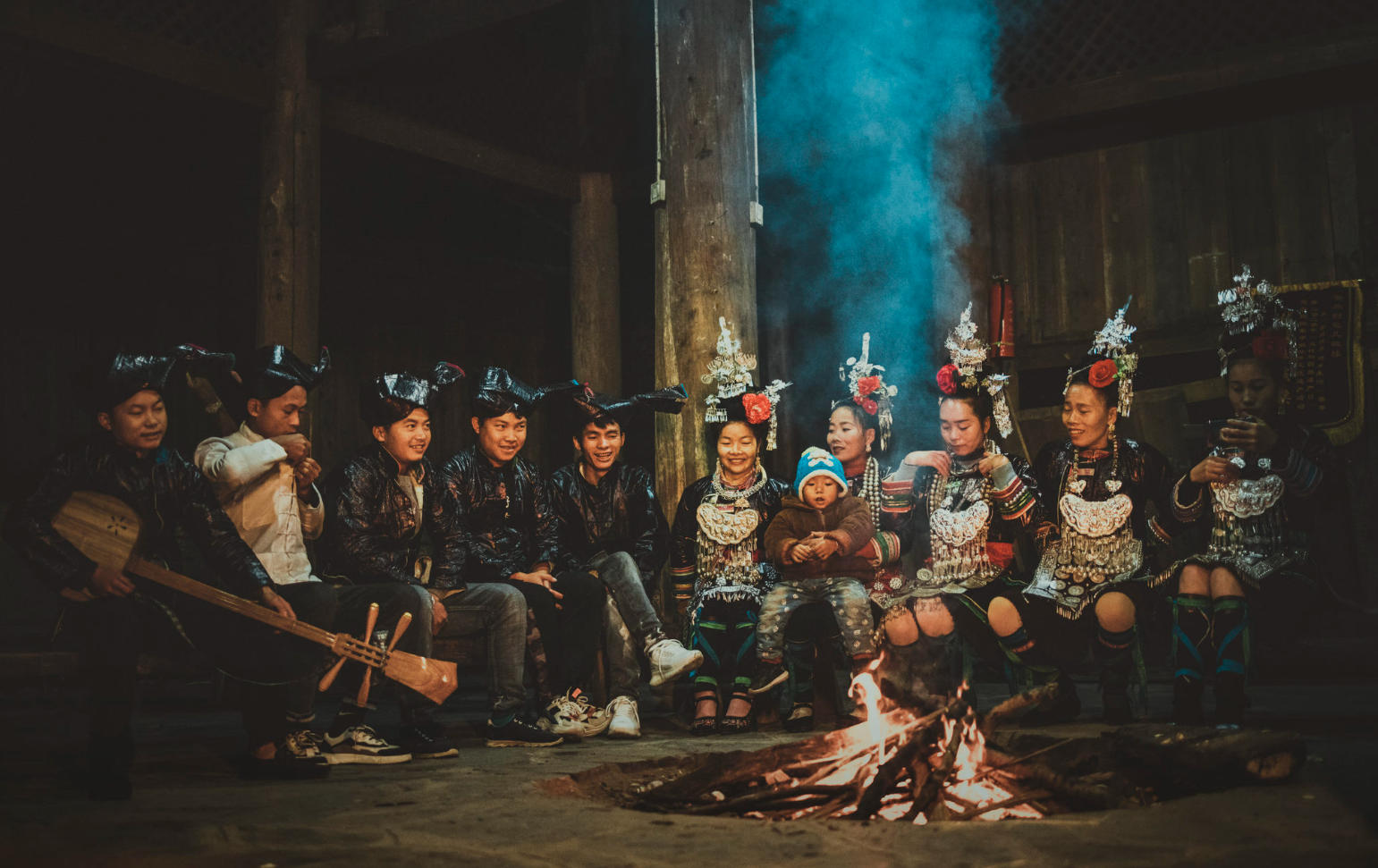 Dong singers seated inside a traditional wooden drum tower in Huanggang Dong Village, performing together.