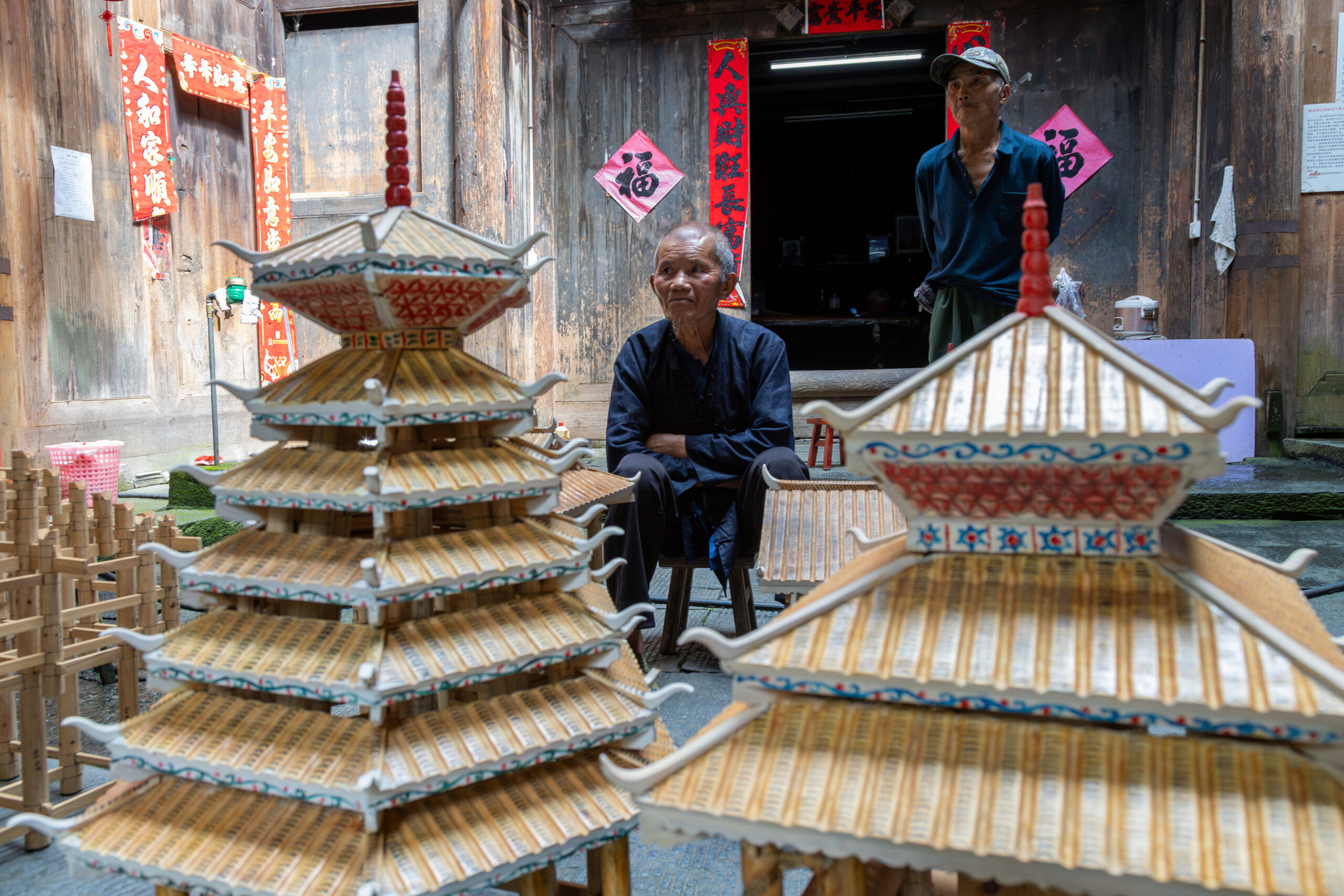 An elderly Dong master carpenter in Dali Dong Village, locally known as a "zhangmoshi," known for building traditional wooden structures without nails or blueprints.