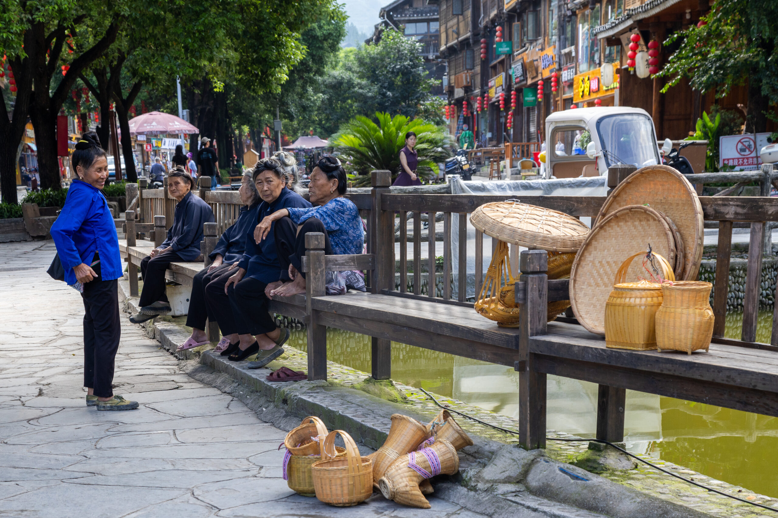 Elderly Dong villagers sitting and chatting along a stone-paved street in Zhaoxing Dong Village.
